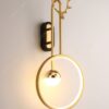 đèn gắn tường có thiết kế thân đèn uốn cong kết hợp với vòng tròn, thân đèn bằng đồng mạ vàng, nguồn sáng là bóng đèn led và dây đèn led bên trong vòng tròn