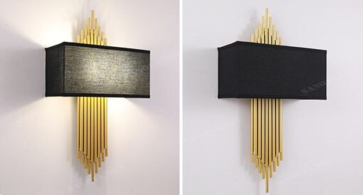 chiếc đèn ốp tường có thiết kế thânđèn là những ống xếp sát vàng đồng và chao đèn vải hình hộp chữ nhật