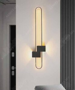 một chiếc đèn gắn tường có kiểu dáng là một hình bầu dục thanh mảnh kết hợp với một hộp ốp tường bằng sắt sơn tĩnh điện chiếc đèn với tông màu đen cá tính và hiện đại