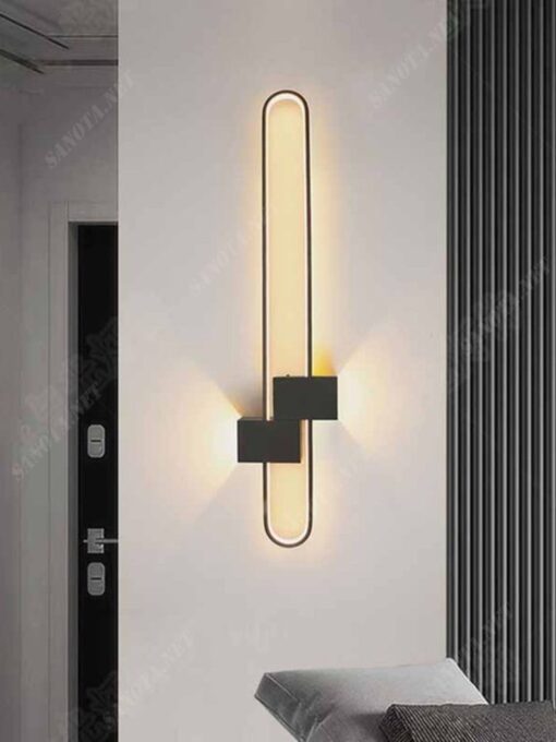 một chiếc đèn gắn tường có kiểu dáng là một hình bầu dục thanh mảnh kết hợp với một hộp ốp tường bằng sắt sơn tĩnh điện chiếc đèn với tông màu đen cá tính và hiện đại