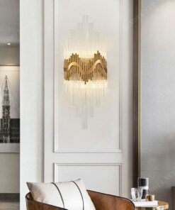 chiếc đèn gắn tường với thiết kế là những ống thuỷ tinh trong suốt được cố định chắc chắn vào tường bằng những thanh dồng mã vàng ốp tường, một sự kết hợp sang trọng và tinh tế