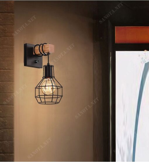 một chiếc đèn gắn tường với thiết kế mang đậm chất cổ điển nhưng pha chút hiện đại kiểu dáng là một lồng đèn được làm từ sắt sơn tĩnh điện màu đen, chiếc lồng đèn được cố định với khúc gỗ trên tường một cách chắc chắn, thiết kế này mang đến cho chiếc đèn mang vẻ đẹp cổ điển độc đáo sang trọng
