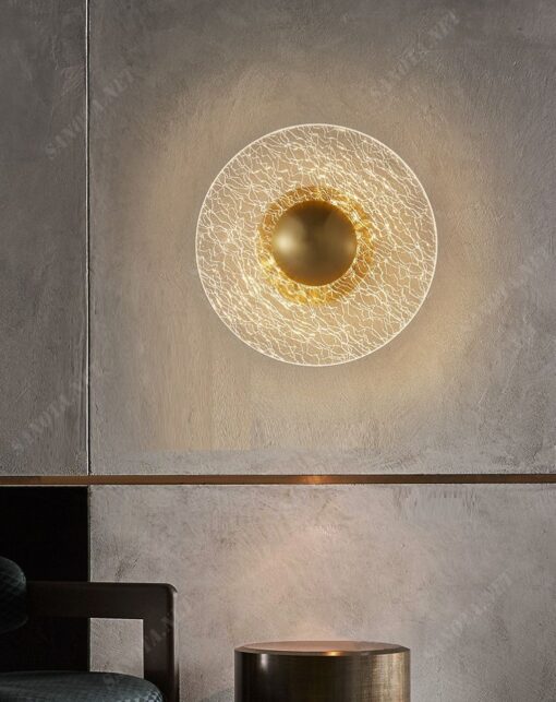 một chiếc đèn gắn tường với thiết kế hiện đại và sang trọng là một mâm đèn led có viền ngoài làm từ chất liệu thuỷ tinh trong suốt có nhưng vân đá độc đáo, chính giữa là điểm nhấn đồng mạ vàng được thiết kế để chiếc đèn có thể được gắn cố định chắc chắn trên tường, đây sẽ là một chiếc đèn phù hợp cho mọi không gian nội thất đặc biệt là phòng ngủ bởi ánh sáng dịu nhẹ và ấm áp mà nó đem lại