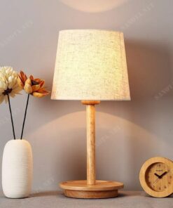 một chiếc đèn để bàn với thân gỗ trụ tròn kết hợp với chao vải, chiếc đèn là sự kết hợp hài hoà của nét đẹp hiện đại, với chao vải ánh sáng ra từ chiếc đèn mềm mại ấm áp