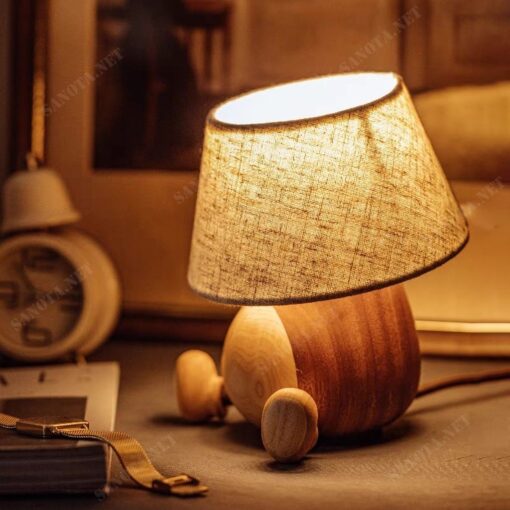 chiếc đèn để bàn hiện đại với thiết kế đơn giản sử dụng chất liệu thân đèn bằng gỗ và chao vải, chiếc đèn sẽ vừa là chiếc đèn thắp sáng cho không gian sống của bạn vừa là món đồ trang trí tạo nên một điểm nhấn đặc biệt thu hút sự chú ý của mọi người. Không gian nội thất hay ngoại thất là điều bạn lưu tâm nhất trong việc tạo ra không gian sống. Một không gian được bày bố hợp với ý tưởng của bạn là điều tuyệt vời. Sẽ tuyệt vời hơn nếu không gian ấy được màu sắc của ánh sáng chiếu rọi. Chiếc đèn bàn gỗ này sẽ là lựa chọn lý tưởng cho không gian sống năng động tươi trẻ của bạn, phù hợp cho phòng ngủ ấm áp, hay phòng khách sang trọng, cả phòng làm việc hiện đại. Với sự phong phú về kiểu dáng thiết kế, ngôi nhà bạn sẽ thêm xinh đẹp. Với công nghệ chiếu sáng hiện đại, không gian của bạn sẽ bừng sáng nổi bật
