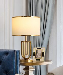 một chiếc đèn để bàn theo văn phong review với thiết kế của chiếc đèn hiện đại và sang trọng, sự kết hợp độc đáo của thân đèn được xi vàng bóng và chao vải, với thiết kế này đem đến một cái nhìn độc đáo vừa là món đồ decor sang trọng vừa đem đến nguồn ánh sáng ấm áp và dễ chịu cho không gian nội thất, chiếc đèn này sẽ là điểm nhấn tinh tế cho phòng khách tôn lên vẻ đẹp nội thất sang trọng, ngoài ra còn được đặt ở những căn phòng ngủ, những khách sạn,resort đem đến nguồn ánh sáng ấm áp dễ chịu để nghủ ngơi thư giãn, đây chắc chắn sẽ là một chiếc đèn để bàn mà bạn đang tìm kiếm