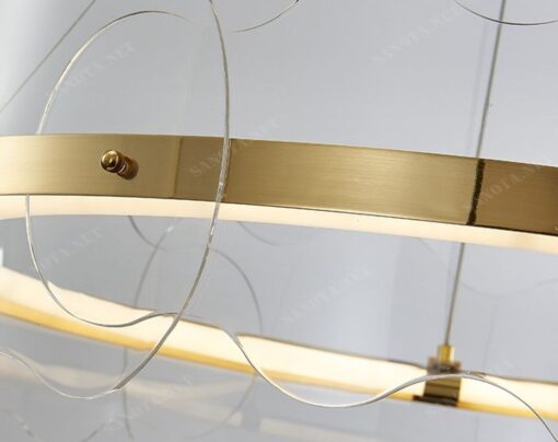 Một chiếc đèn chùm LED hiện đại với thiết kế hợp kim mạ vàng sang trọng được treo cố định trên trần nhà. Một tác phẩm nghệ thuật ánh sáng đầy thu hút. Sự độc đáo của nó không chỉ đến từ kiểu dáng vô cùng tinh tế. Mà còn từ hoạ tiết gợn sóng tinh xảo được đính trên vòng tròn đèn LED. Tạo nên một điểm nhấn rực rỡ và quyến rũ cho chiếc đèn.