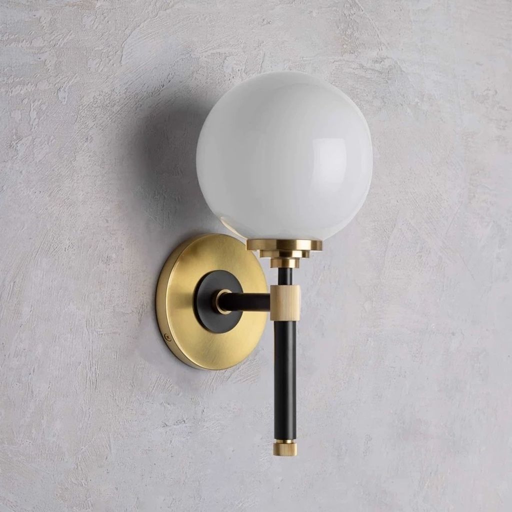 Chiếc đèn gắn tường LED này không chỉ là một nguồn sáng mà còn là một tác phẩm nghệ thuật hiện đại. Với thiết kế tối giản nhưng đầy tinh tế. Chiếc đèn này mang đến không gian một vẻ đẹp hiện đại và sang trọng. Thân đèn được làm từ một thanh hợp kim mạ vàng quý phái. Được cố định mạnh mẽ bởi một đế đèn chắc chắn trên tường. Điểm độc đáo của chiếc đèn nằm ở bóng đèn chao thuỷ tinh. Hình dạng như một viên đá cẩm thạch, tạo điểm nhấn thu hút cho toàn bộ thiết kế.