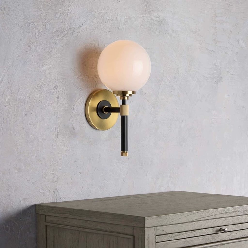 Chiếc đèn gắn tường LED này không chỉ là một nguồn sáng mà còn là một tác phẩm nghệ thuật hiện đại. Với thiết kế tối giản nhưng đầy tinh tế. Chiếc đèn này mang đến không gian một vẻ đẹp hiện đại và sang trọng. Thân đèn được làm từ một thanh hợp kim mạ vàng quý phái. Được cố định mạnh mẽ bởi một đế đèn chắc chắn trên tường. Điểm độc đáo của chiếc đèn nằm ở bóng đèn chao thuỷ tinh. Hình dạng như một viên đá cẩm thạch, tạo điểm nhấn thu hút cho toàn bộ thiết kế.