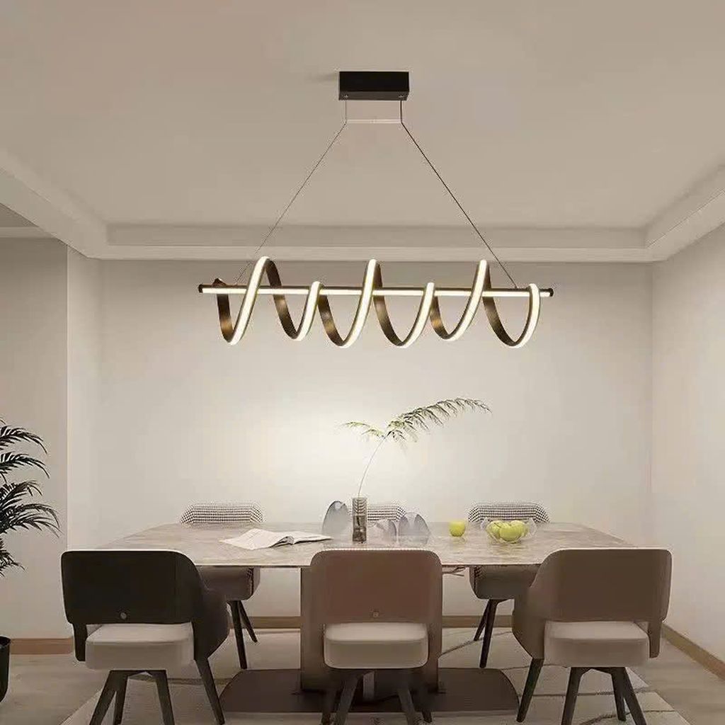 Đèn chùm bàn ăn với hình dáng uốn lượn như một dải sóng ánh sáng mềm mại, chiếc đèn chùm này tạo nên một hiệu ứng thị giác ấn tượng, mang đến sự sang trọng và phá cách cho không gian bàn ăn. Thiết kế xoắn ốc cách điệu kết hợp giữa tone đen nhám tinh tế và ánh sáng LED trắng dịu nhẹ giúp không gian thêm phần ấm cúng nhưng vẫn toát lên vẻ hiện đại, thanh lịch.