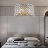 Đèn chùm thả trần này được thiết kế với kiểu dáng đối xứng, kết hợp giữa khung kim loại mạ vàng sang trọng và hệ thống pha lê cao cấp, tạo nên một tổng thể hài hòa, thanh lịch nhưng vẫn đầy cá tính. Các hạt pha lê được cắt gọt tỉ mỉ như những giọt sương lấp lánh, mỗi khi ánh sáng lan tỏa, chúng phản chiếu thành những vệt sáng lung linh, đưa cả không gian nghỉ ngơi bước vào một thế giới đầy chất thơ và ấm áp.