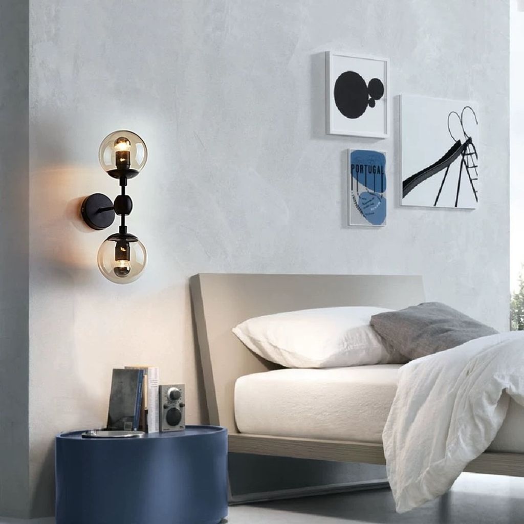 Đèn tường hiện đại này chinh phục người nhìn bởi phong cách thiết kế theo xu hướng tối giản (minimalist) nhưng vẫn nổi bật với dấu ấn riêng. Hai quả cầu thủy tinh màu khói không chỉ giúp khuếch tán ánh sáng mềm mại, mà còn tạo nên hiệu ứng thị giác ấm áp, dễ chịu. Lý tưởng cho các không gian như phòng khách, phòng ngủ, hành lang, hay khu vực đọc sách.