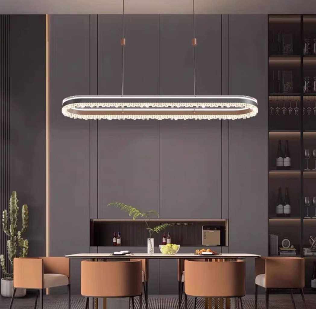Đèn chùm pha lê thiết kế oval mềm mại giúp tạo nên cảm giác cân đối, hài hòa cho không gian bàn ăn. Đường viền tinh tế được tô điểm bằng lớp pha lê sắc sảo. Mang lại hiệu ứng ánh sáng lung linh và huyền ảo, khiến mỗi bữa ăn trở nên ấm cúng và đầy cảm xúc. Sự kết hợp hoàn hảo giữa tone màu đen tuyền sang trọng và chất liệu kim loại cao cấp tạo nên tổng thể mạnh mẽ, nhưng không kém phần thanh lịch.