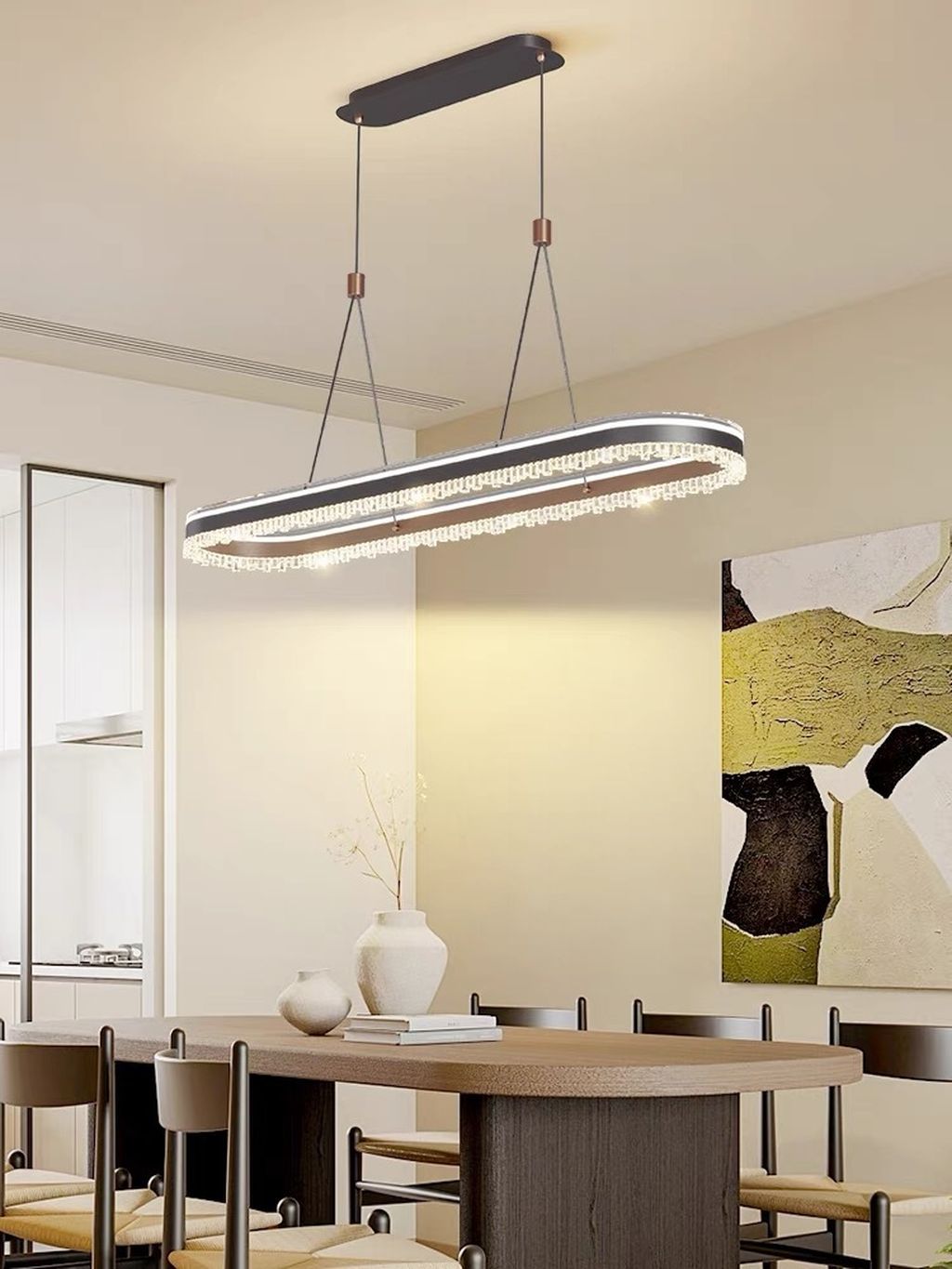 Đèn chùm pha lê thiết kế oval mềm mại giúp tạo nên cảm giác cân đối, hài hòa cho không gian bàn ăn. Đường viền tinh tế được tô điểm bằng lớp pha lê sắc sảo. Mang lại hiệu ứng ánh sáng lung linh và huyền ảo, khiến mỗi bữa ăn trở nên ấm cúng và đầy cảm xúc. Sự kết hợp hoàn hảo giữa tone màu đen tuyền sang trọng và chất liệu kim loại cao cấp tạo nên tổng thể mạnh mẽ, nhưng không kém phần thanh lịch.