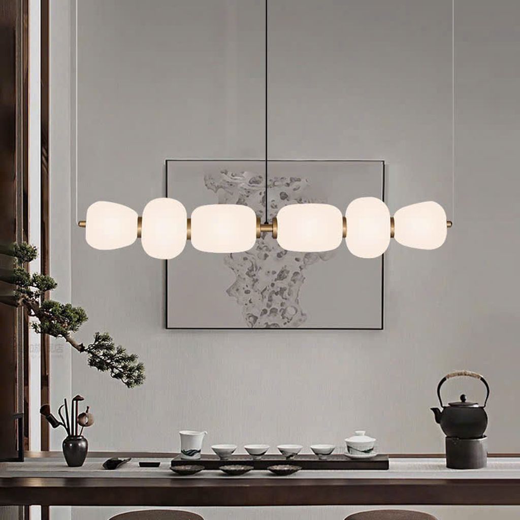 Đèn chùm chao thuỷ tinh sang trọng với thiết kế đèn chùm được lấy cảm hứng từ phong cách tối giản Á Đông. Với thân đèn kim loại mạ đồng ánh vàng sang trọng, kết nối khéo léo với từng chao đèn thủy tinh mờ có hình dáng độc đáo. Những đường cong mềm mại xen kẽ theo nhịp điệu tạo cảm giác nhịp nhàng như một chuỗi ngọc tinh xảo treo lơ lửng giữa không trung.