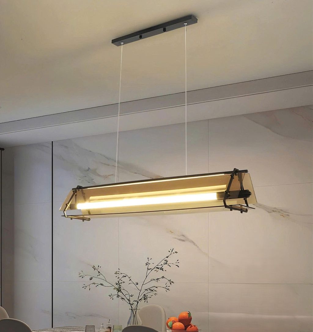 Đèn chùm bàn ăn sở hữu thiết kế hình hộp chữ nhật độc đáo. Kết hợp cùng chao đèn màu trà thanh lịch và khung kim loại màu đen mạnh mẽ. Chiếc đèn mang đến vẻ đẹp vừa hiện đại vừa có chút hoài cổ, tạo nên một tổng thể hài hòa, bắt mắt. Lớp chao trà không chỉ giúp điều chỉnh ánh sáng ấm áp lan tỏa dịu nhẹ khắp không gian mà còn tăng cảm giác ấm cúng. Gắn kết giữa các thành viên trong mỗi bữa ăn gia đình.