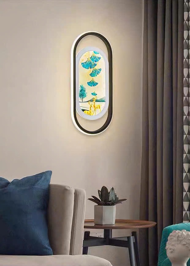 Đèn tường trang trí gây ấn tượng ngay từ ánh nhìn đầu tiên với thiết kế khung oval bo tròn mềm mại. Bao bọc bên trong là bức tranh nghệ thuật đầy ý nghĩa với hình ảnh chú hươu và cây cối. Biểu tượng cho sự thịnh vượng, bình an và phát triển. Hệ thống ánh sáng LED hiện đại được lồng ghép khéo léo, tạo hiệu ứng chiếu sáng dịu nhẹ. Vừa mang đến cảm giác ấm áp vừa tôn lên vẻ đẹp của bức tranh bên trong.