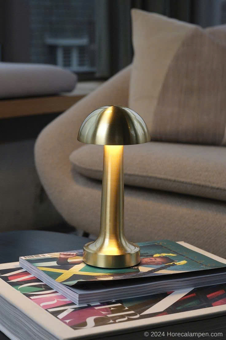 Đèn để bàn mạ vang lấy cảm hứng từ hình dáng cây nấm nhỏ xinh. Đèn để bàn nổi bật với thiết kế tối giản, gọn gàng mà vẫn tinh tế đến từng đường nét. Toàn bộ thân đèn được phủ lớp mạ vàng bóng mượt, phản chiếu ánh sáng nhẹ nhàng. Tạo cảm giác ấm áp và sang trọng cho căn phòng.