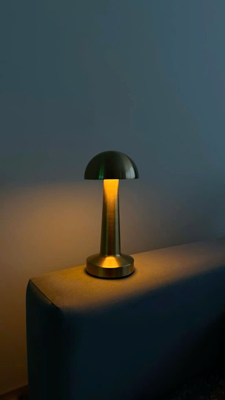 Đèn để bàn mạ vang lấy cảm hứng từ hình dáng cây nấm nhỏ xinh. Đèn để bàn nổi bật với thiết kế tối giản, gọn gàng mà vẫn tinh tế đến từng đường nét. Toàn bộ thân đèn được phủ lớp mạ vàng bóng mượt, phản chiếu ánh sáng nhẹ nhàng. Tạo cảm giác ấm áp và sang trọng cho căn phòng.